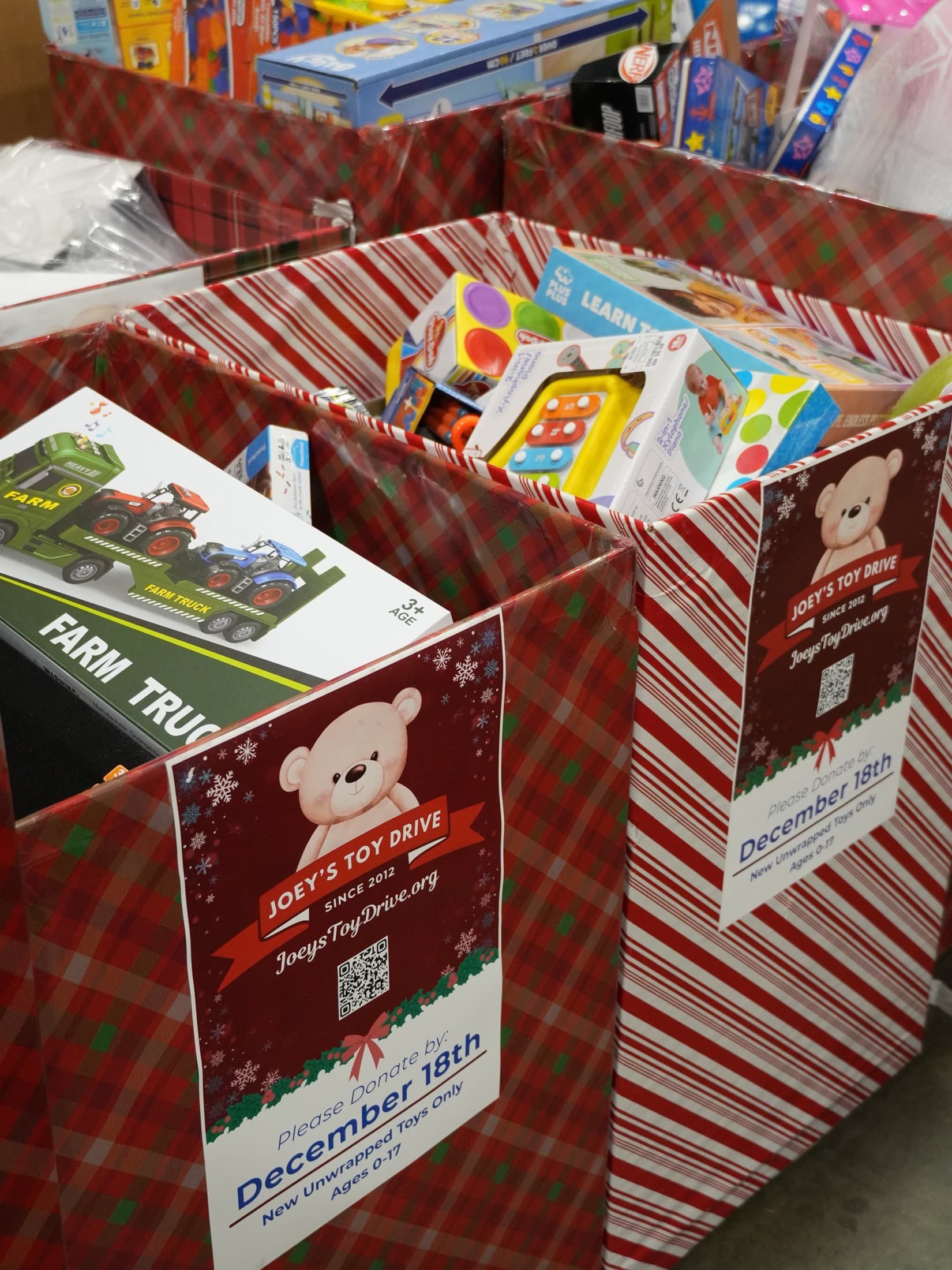Two collection boxes in plaid and candy-stripe wrap, filled past the brim with new toys