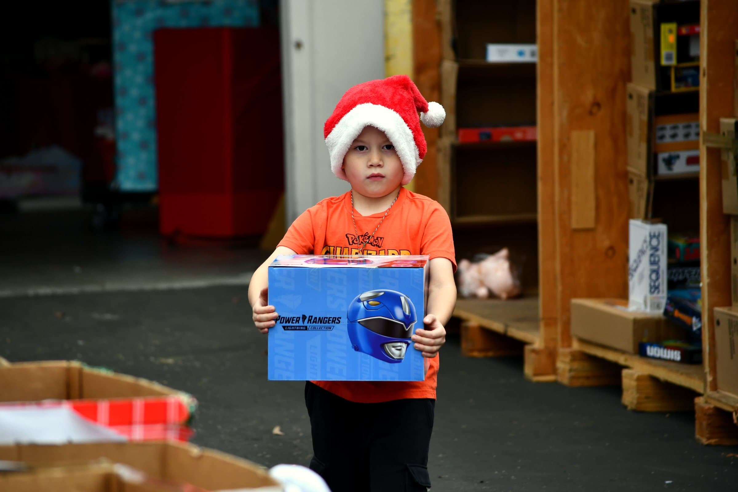 A young boy in a Santa hat carries the new toy he just received