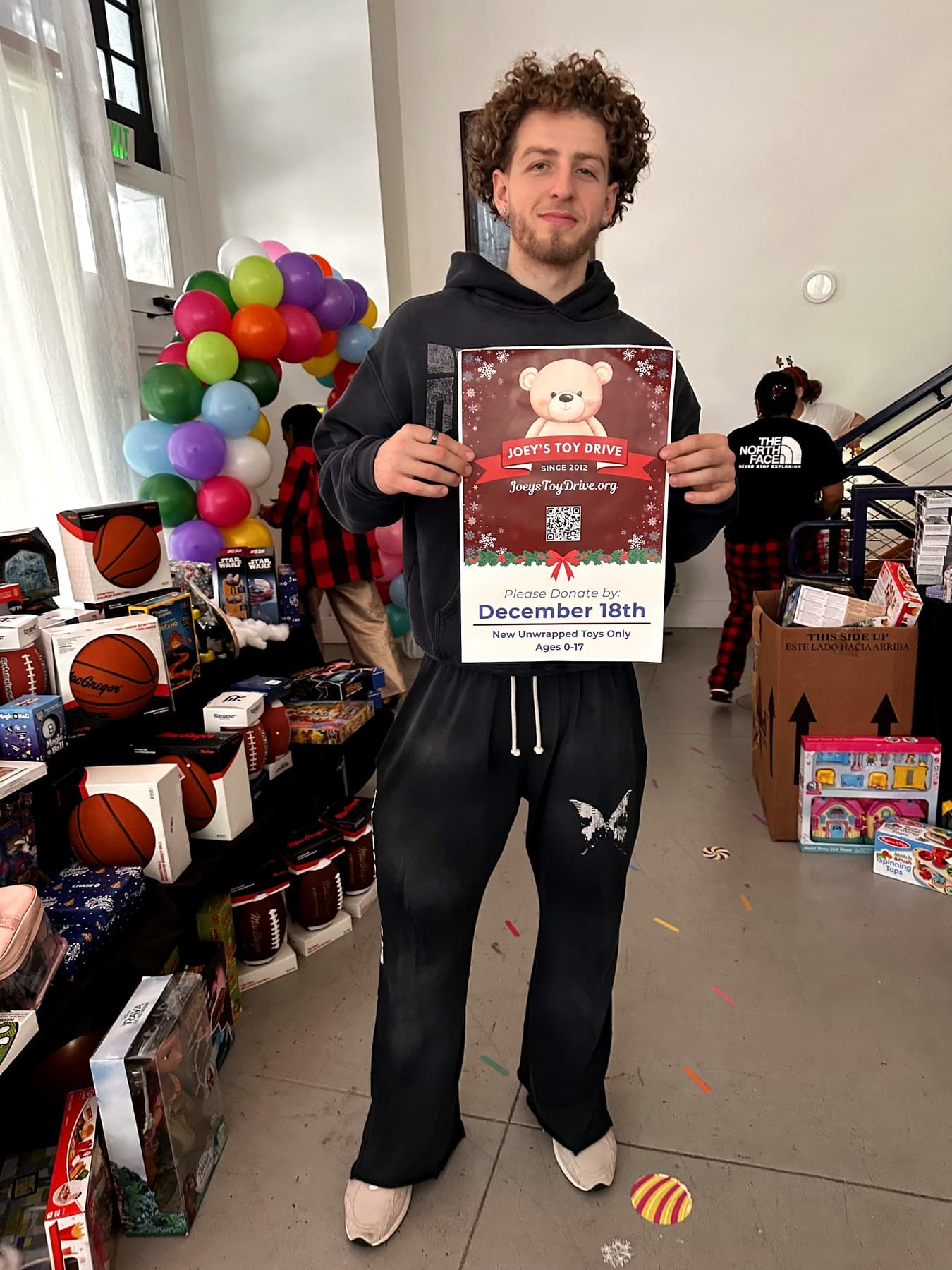 A Joey's Toy Drive volunteer holding a drive flyer at the warehouse