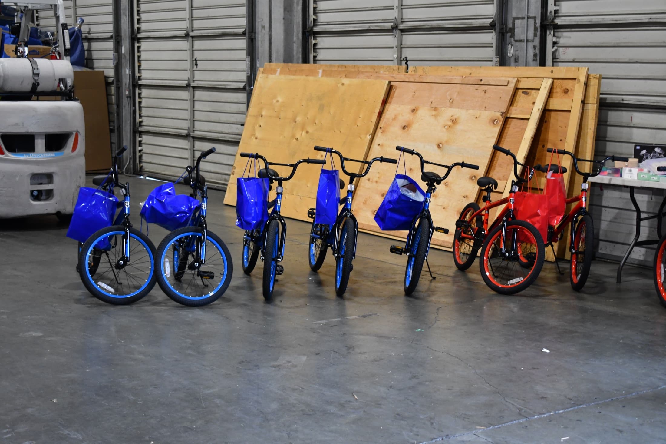 A row of new bikes with gift bags on their handlebars, lined up inside the warehouse