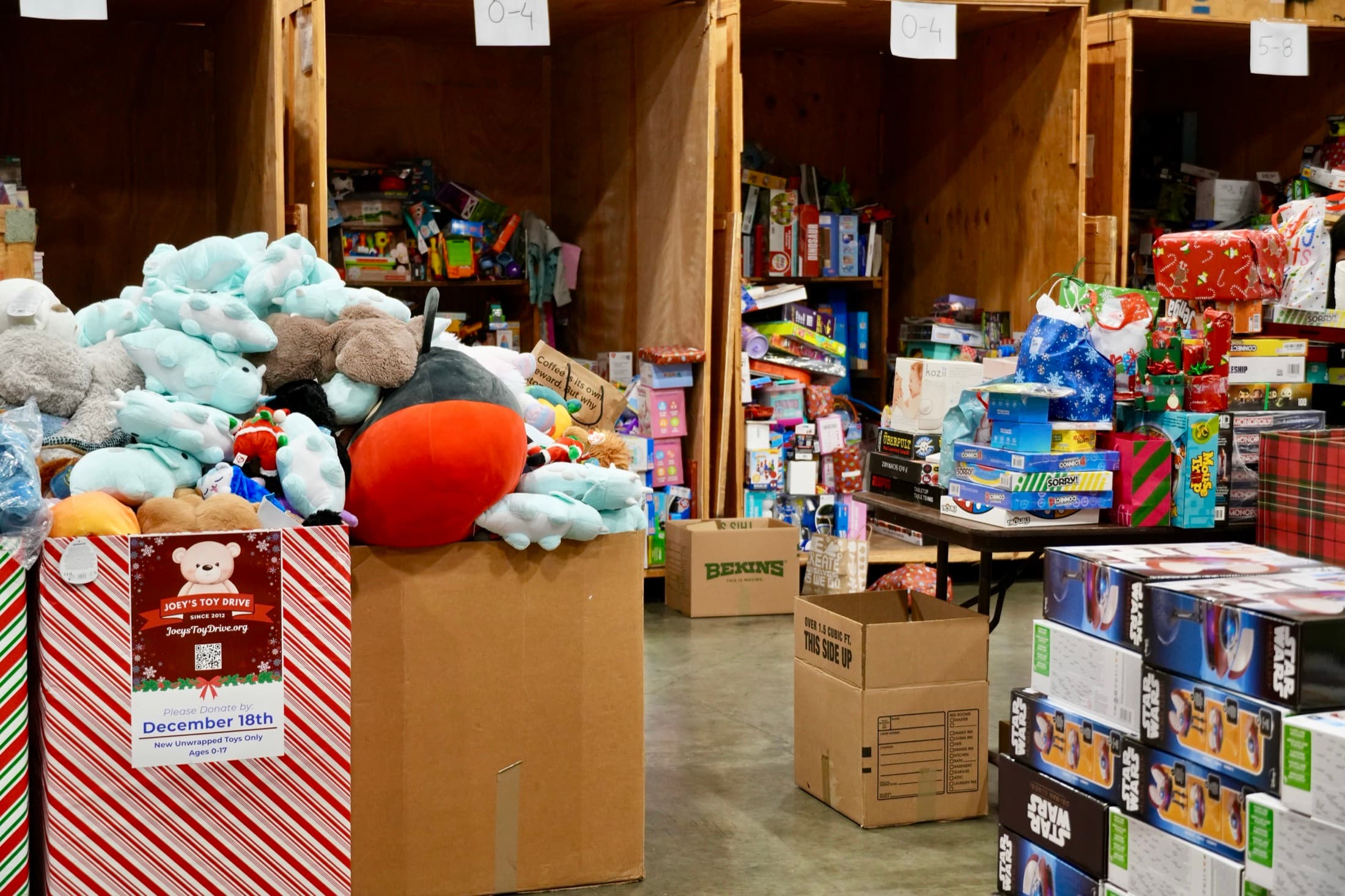 A collection box overflowing with stuffed animals beside aisles of sorted toys