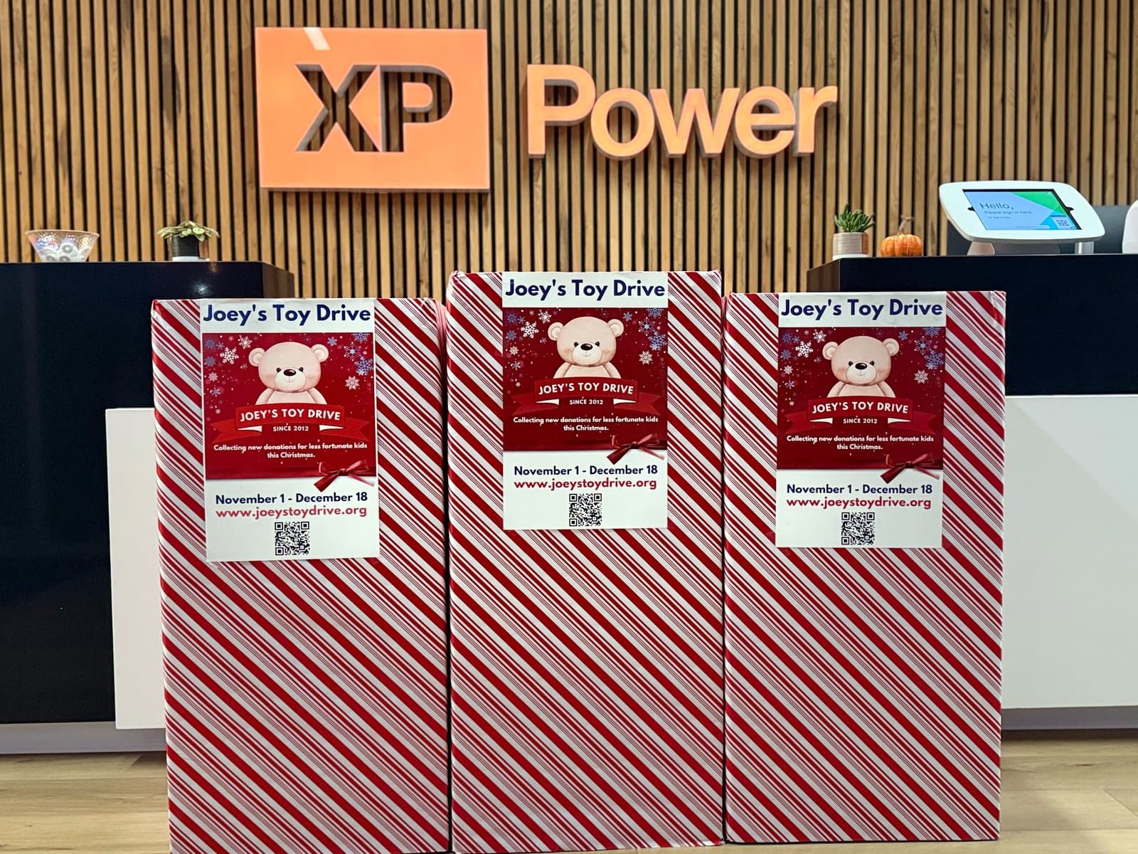 Candy-cane striped Joey's Toy Drive collection boxes lined up at a company reception desk